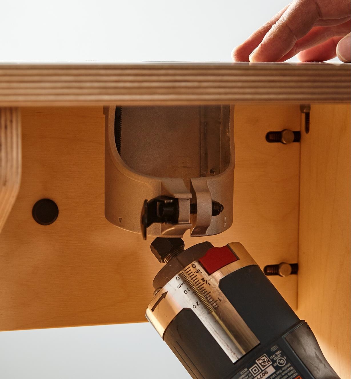 Removing a compact router to change bits without separating the sleeve and base plate from the table